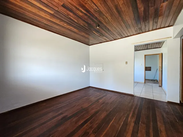 Vista interna de uma sala com piso de madeira escura e teto de madeira.