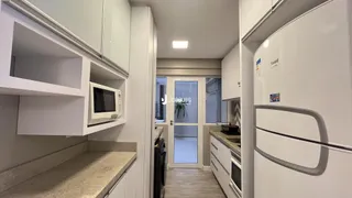Interior de uma cozinha com armários brancos e bancadas claras.