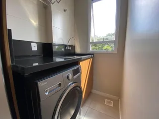 Foto de um banheiro com bancada escura e máquina de lavar roupa.