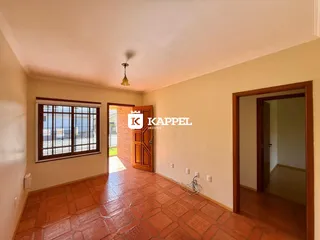 Uma sala de estar com piso de cerâmica avermelhada e janela grande.