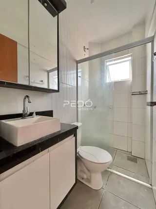 Foto interna de um banheiro com box de vidro e vaso sanitário.