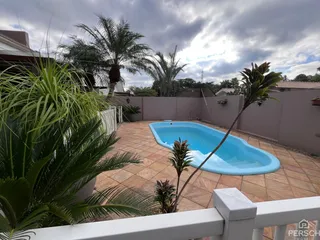 Foto de uma piscina azul em um pátio com vegetação tropical.