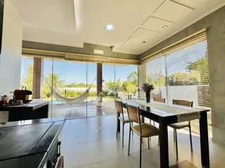 Sala de jantar com vista para o jardim e piscina através de portas de vidro.