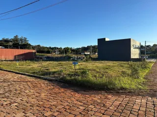 Vista externa de um terreno gramado com um edifício moderno ao fundo.