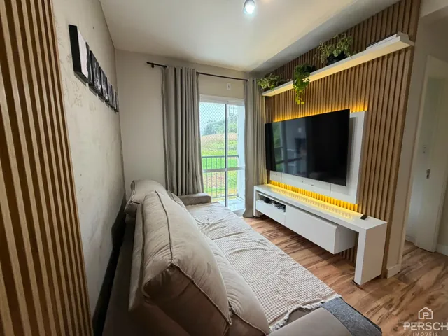 Sala de estar com sofá e televisão em ambiente moderno.