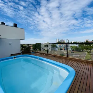 Piscina azul e deck de madeira em uma área externa com vista para a cidade.