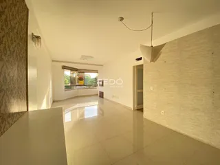 Ambiente interno de uma sala ampla com piso claro e paredes brancas.