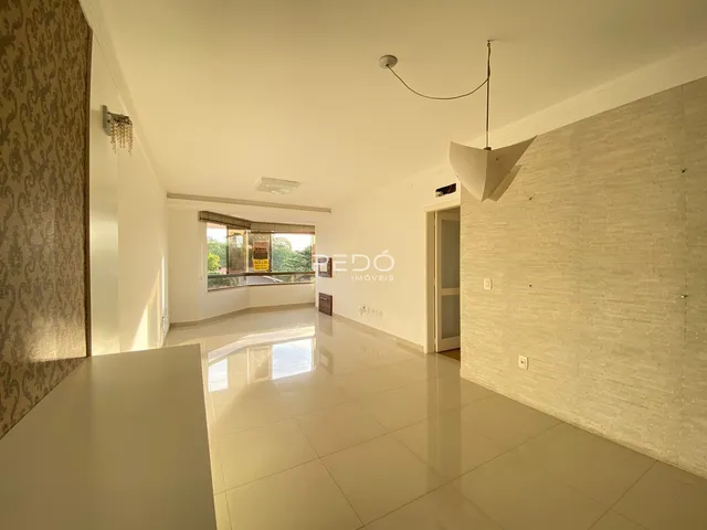 Ambiente interno de uma sala ampla com piso claro e paredes brancas.