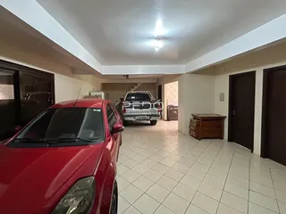 Imagem interna de uma área com piso de cerâmica e um carro vermelho em primeiro plano.