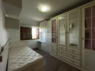 Quarto com armários embutidos e cabeceira em um imóvel.