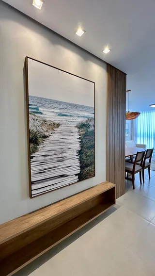 Uma parede com uma pintura grande e um banco de madeira.
