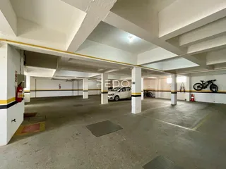 Vista de um estacionamento com estrutura de concreto aparente e colunas.