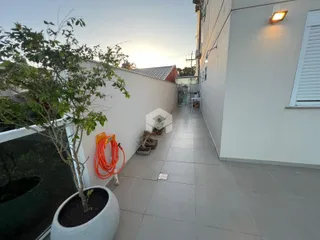 Vista externa de um pátio com piso de cerâmica e vegetação.