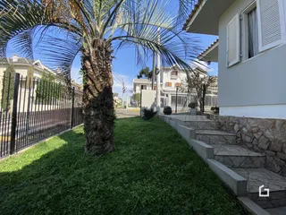 Fachada de uma residência com jardim e cerca de ferro.