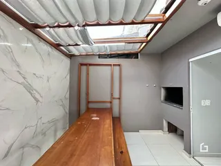 Hall de entrada com piso de madeira e revestimento de mármore branco.