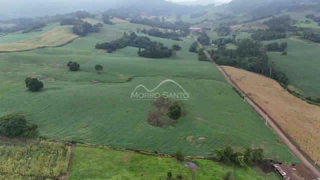 Vista aérea de paisagem rural com campos verdes e trilhos.