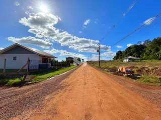 Vista da fachada de uma casa ao lado de uma estrada de terra no interior do Brasil.