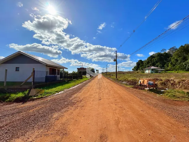 Vista da fachada de uma casa ao lado de uma estrada de terra no interior do Brasil.