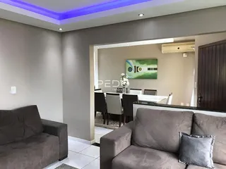 Sala de estar com sofá e abertura para a área de jantar.