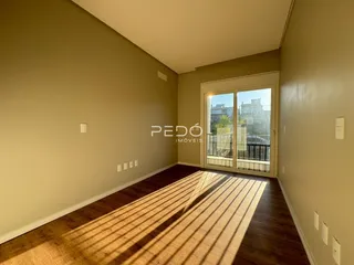 Sala de estar com piso de madeira e porta de vidro iluminada.