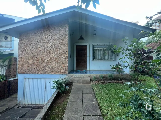 Fachada de uma casa em Lajeado, Brasil, com muro de pedra e portão de metal.
