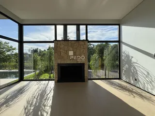 Sala de estar com grandes janelas e lareira de pedra em um imóvel.