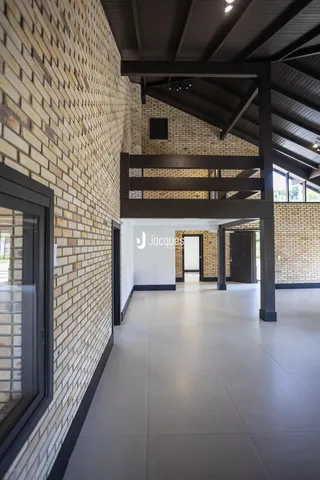 Corredor interno com paredes de tijolo aparente e piso de cerâmica.