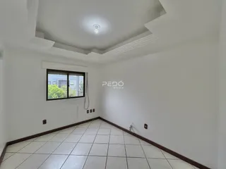 Uma sala de estar com piso de cerâmica clara e paredes brancas.