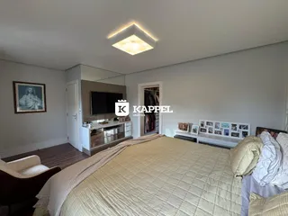 Quarto com cama grande e decoração neutra, apresentando piso de madeira.
