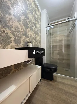 Foto de um banheiro com revestimento de papel de parede ornamentado e box de vidro.