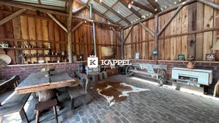 Interior rústico com vigas de madeira e piso de tijolos em uma área comum.