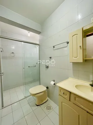 Foto de um banheiro com piso cerâmico e box de vidro.