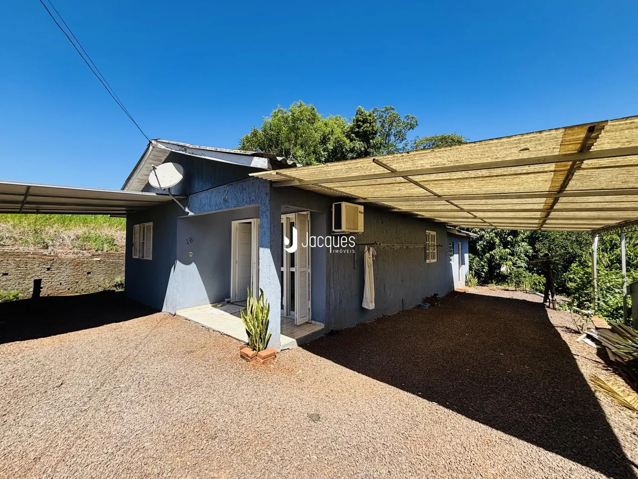 Fachada de uma casa em Lajeado, Brasil, com telhado de zinco e área externa de cascalho.