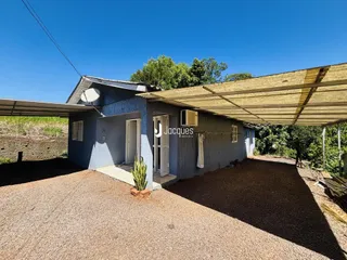 Fachada de uma casa em Lajeado, Brasil, com telhado de zinco e área externa de cascalho.