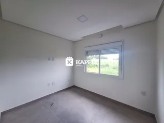 Sala de estar vazia com janela voltada para um campo verde.