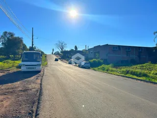 Vista de uma rua rural com um imóvel ao fundo.