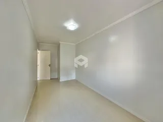 Corredor com paredes claras e piso de madeira.