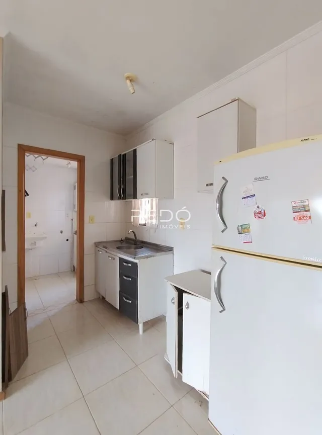Vista da cozinha com armários brancos e piso claro.