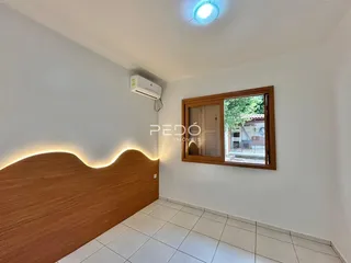 Quarto com parede de madeira e piso cerâmico claro.