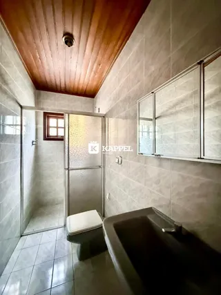 Foto interna de um banheiro com revestimento de azulejos e teto de madeira.