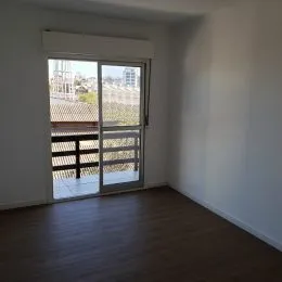 Vista interna de um cômodo com piso de madeira e porta de vidro.