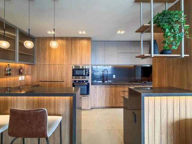Uma cozinha moderna com armários de madeira e iluminação suspensa.