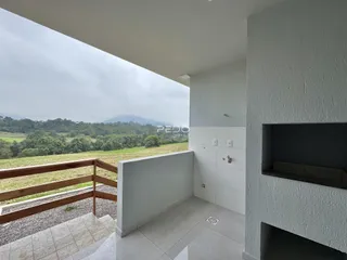 Vista de uma varanda com grade de madeira e paisagem verde ao fundo.
