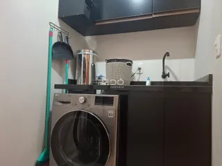 Foto de uma área de cozinha com máquina de lavar roupa e armários.