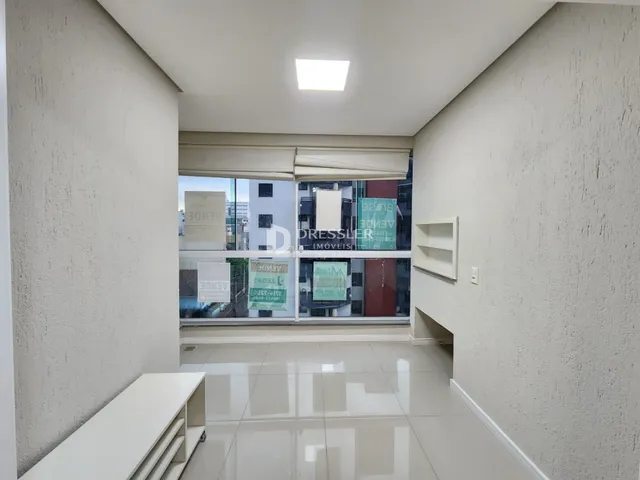 Corredor interno com piso claro e paredes brancas.