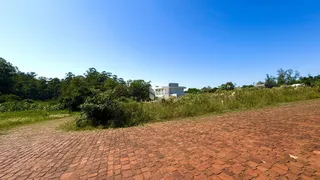 Vista externa de uma propriedade com paisagem verde e pavimento de tijolos.