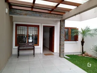 Fachada de uma residência com área coberta e jardim.