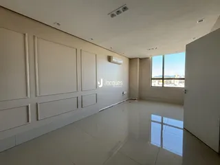 Ambiente interno de uma sala ampla com piso claro e paredes brancas.
