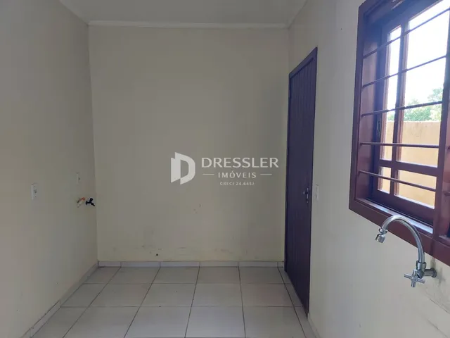 Vista interna de um corredor com piso de cerâmica e porta de madeira.