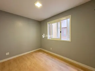 Uma sala de estar com piso de madeira clara e paredes cinzas.